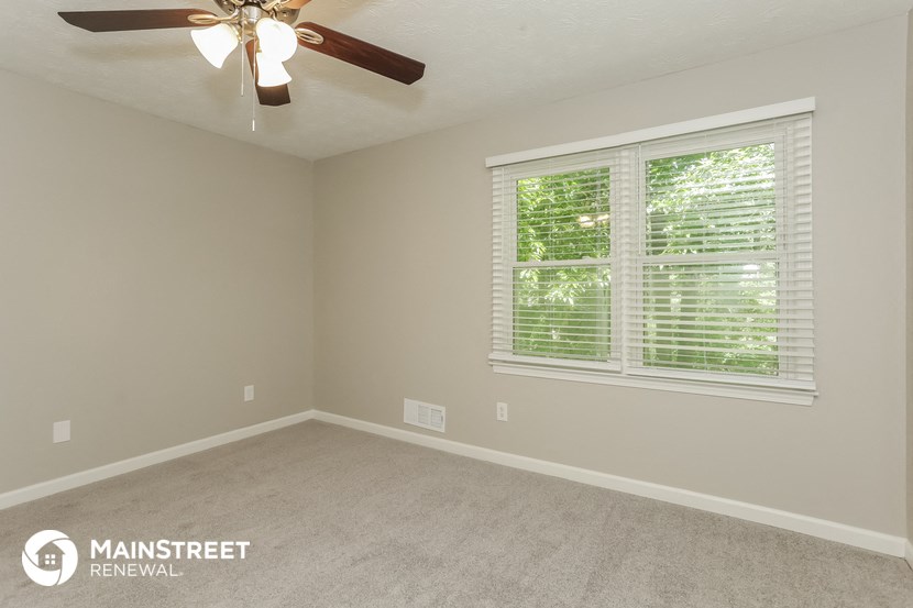 the upstairs bedroom has a ceiling fan and a large window