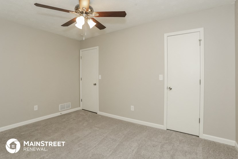 the upstairs bedroom has a ceiling fan and a closet