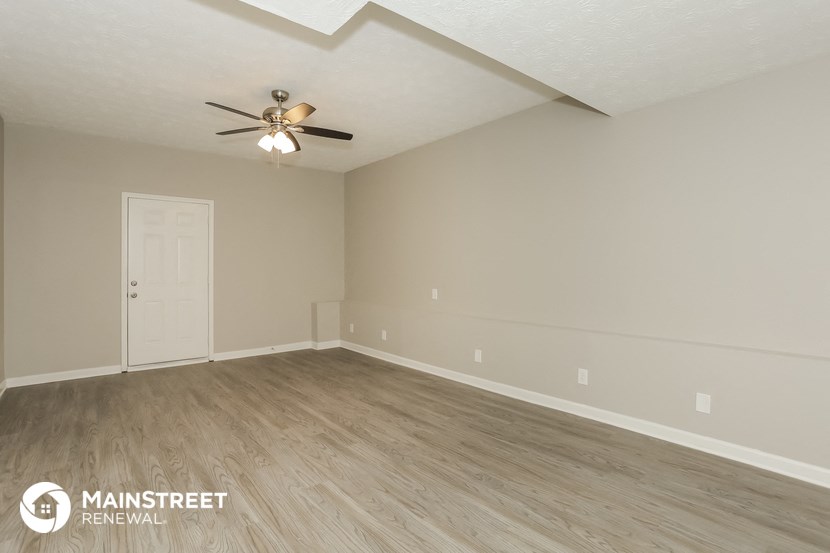 the living room of an empty house with wood floors and a ceiling fan