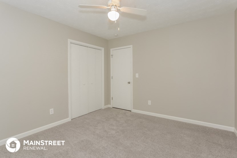 the upstairs bedroom of an apartment with a ceiling fan