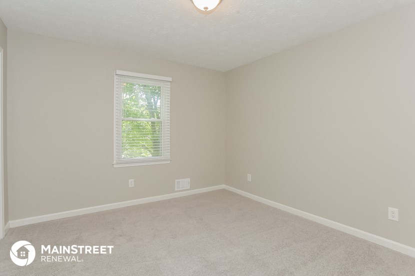 the upstairs bedroom with carpet and a window