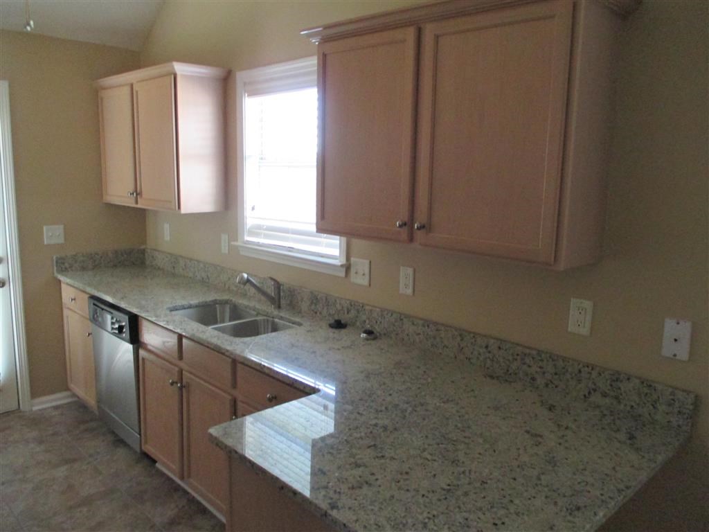 a kitchen with granite counter tops and wooden cabinets