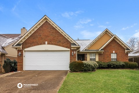 a brick house with a white garage door in front of a lawn