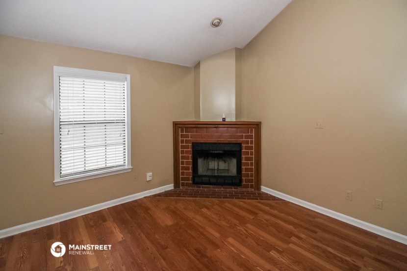 the living room of a house with a fireplace and wooden floors