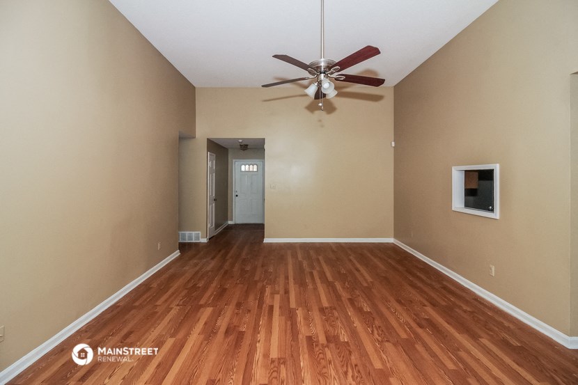 an empty living room with wood flooring and a ceiling fan
