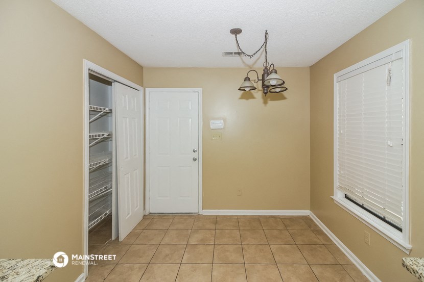 a dining room with a closet and a door to the left and a large window