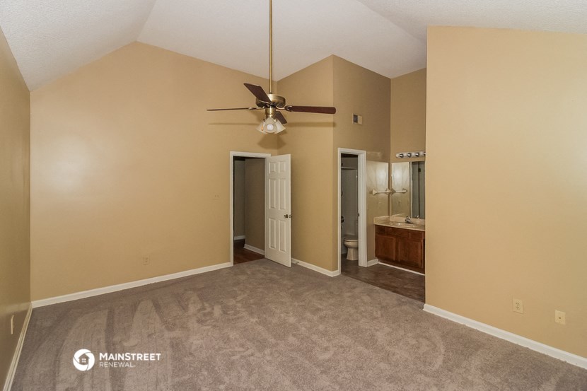 an empty living room with a ceiling fan and a bathroom