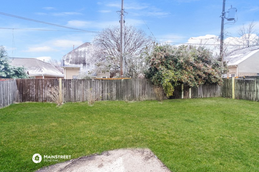 a backyard with a fence and a green lawn