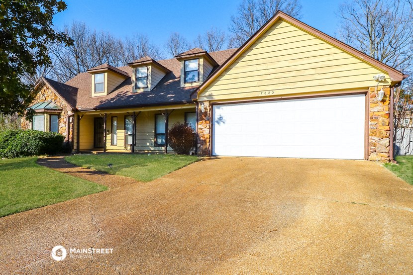a yellow house with a driveway and a white garage door
