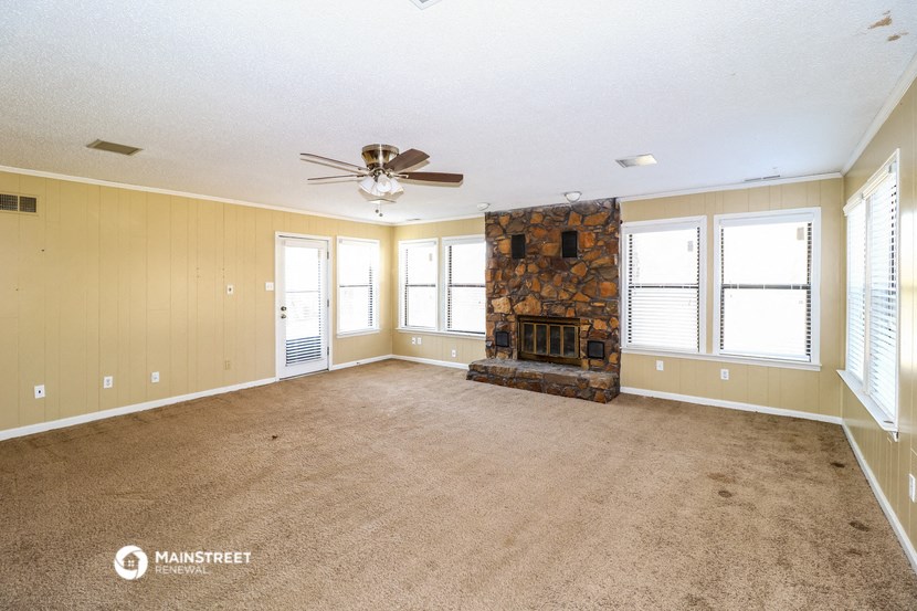 an empty living room with a fireplace and a ceiling fan