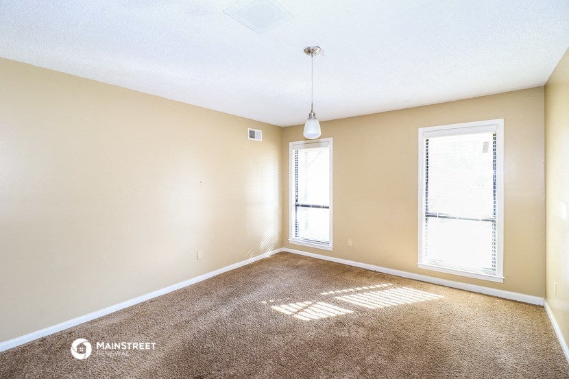 an empty living room with a large window and carpet