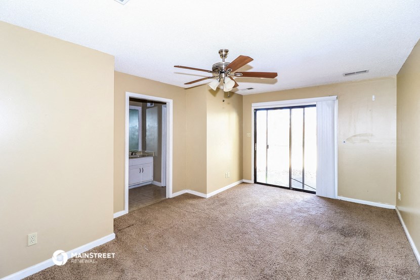 an empty living room with a ceiling fan and a window