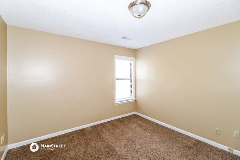 an empty living room with a window and carpet