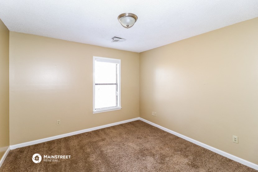 an empty room with a window and carpet