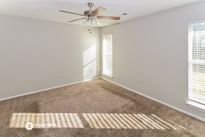 an empty living room with carpet and a ceiling fan