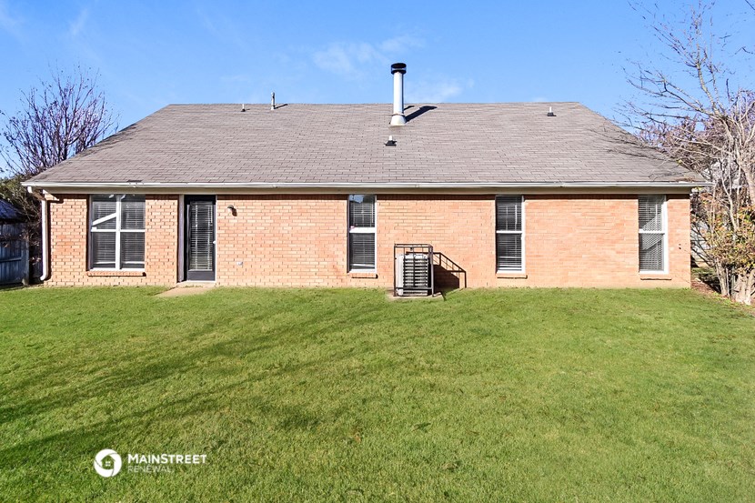 the front of a brick house with a green lawn