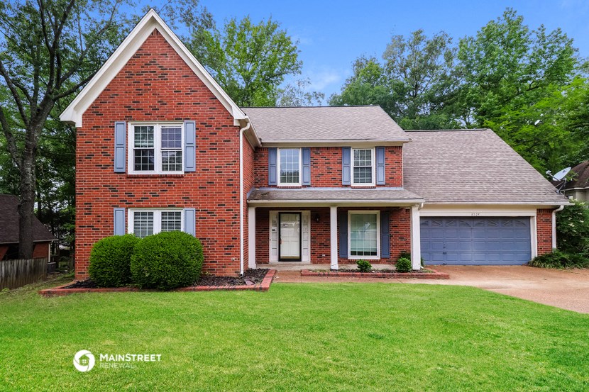 a brick house with a green lawn and a blue garage door