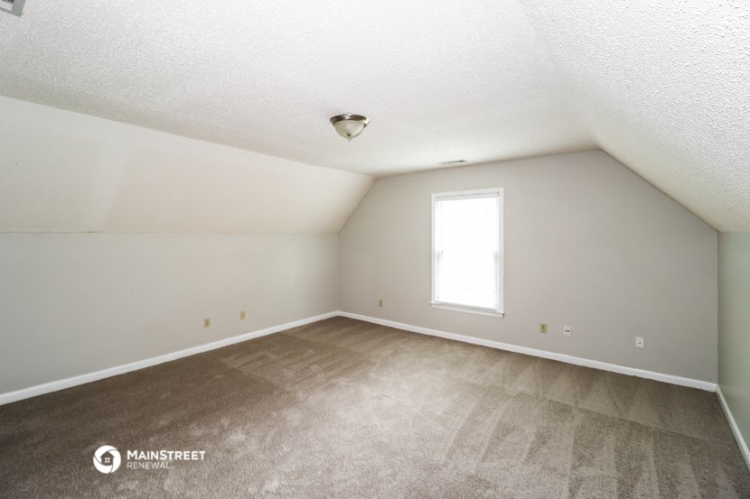the spacious living room with carpeting and a window