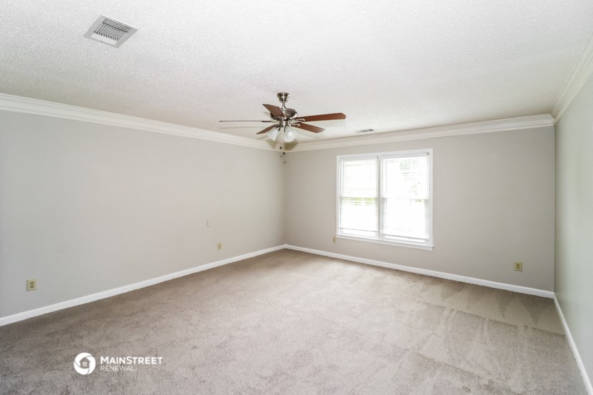 the spacious living room with carpet and ceiling fan