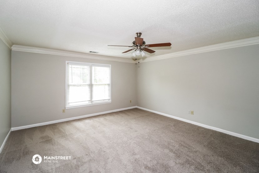 the spacious living room with carpet and ceiling fan