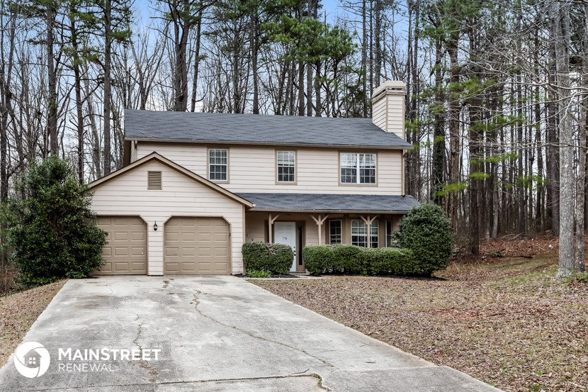 a white house with a garage in the woods