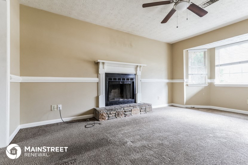 a living room with a fireplace and a ceiling fan