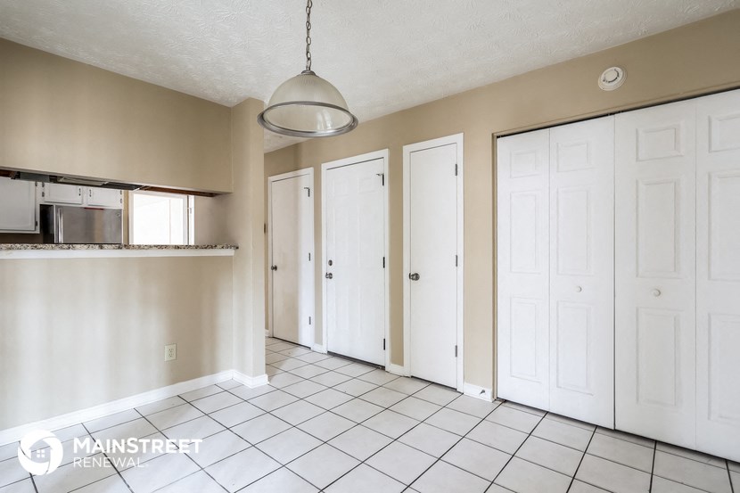 a kitchen with white closets and a tiled floor