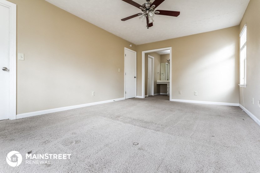 an empty living room with a ceiling fan and carpet