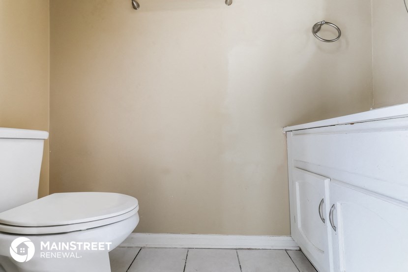 an empty bathroom with a toilet and a cabinet next to it