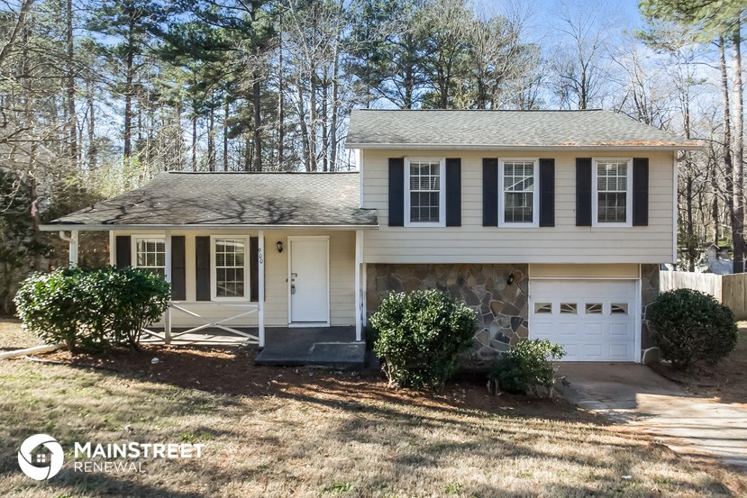 a white house with black shutters and a stone garage door