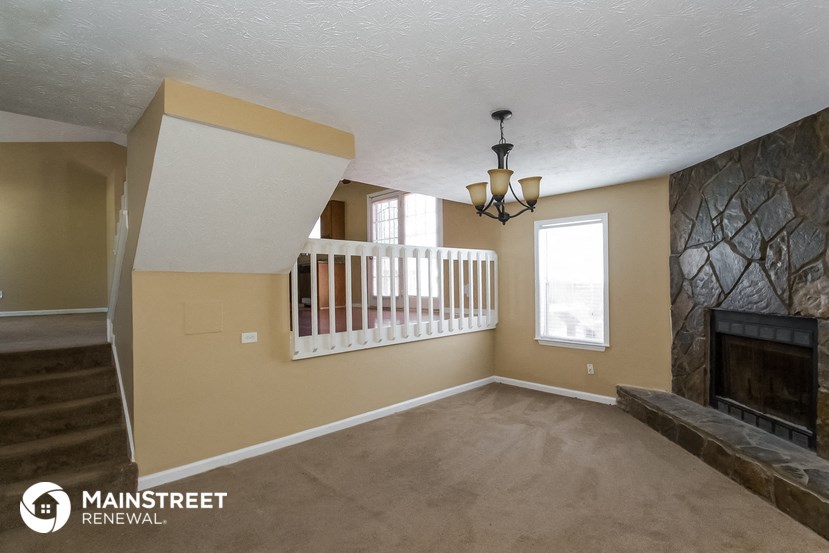 an empty living room with a fireplace and a staircase