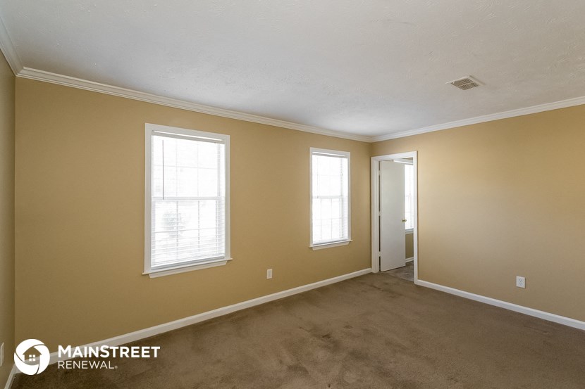 the living room of a home with a carpeted floor and two windows