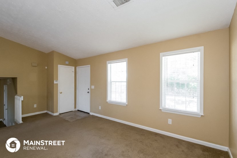 a room with a carpet and two windows and a door