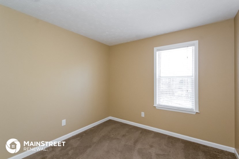a bedroom with a window and a carpeted floor