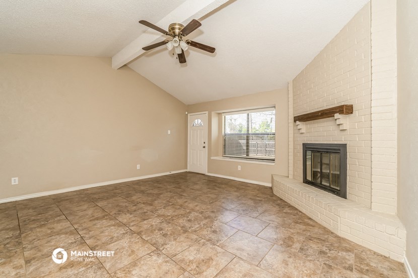 the living room has a fireplace and tile flooring and a ceiling fan