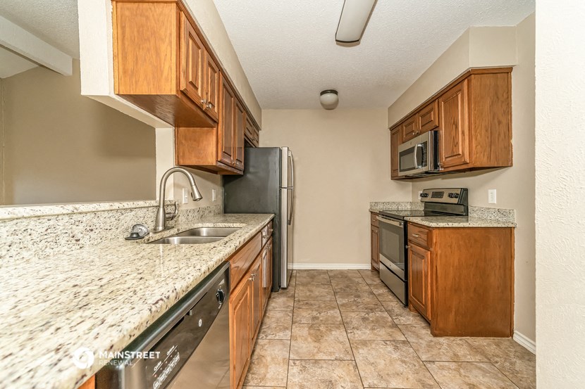 a kitchen with wooden cabinets and granite counter tops and a stainless steel refrigerator