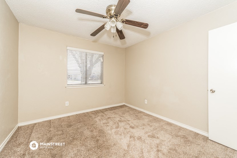 the spacious living room with carpet and a ceiling fan