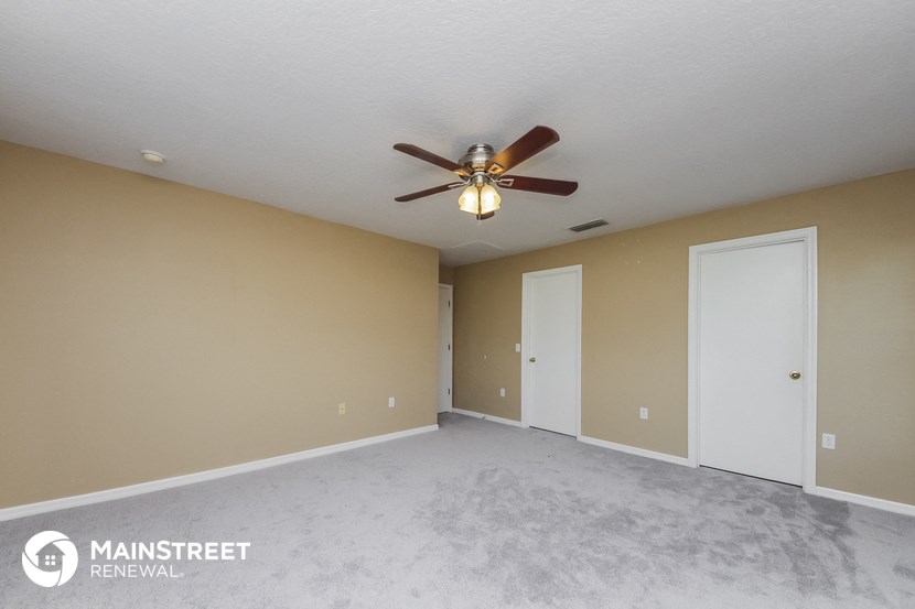 an empty living room with a ceiling fan