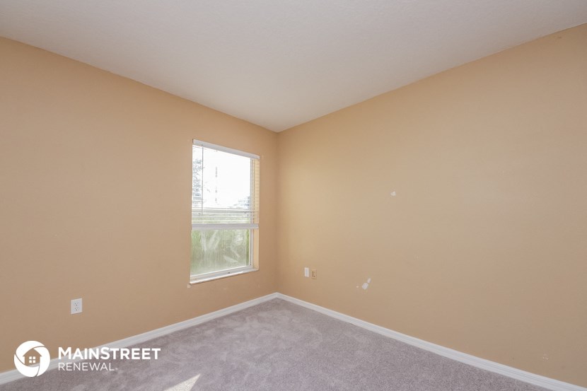 the upstairs bedroom has a large window and carpeted flooring