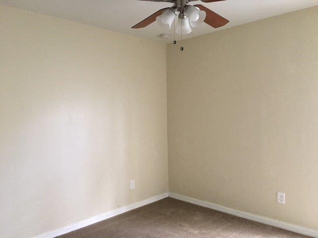 an empty living room with a ceiling fan