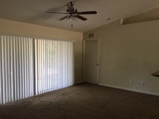 an empty living room with a ceiling fan