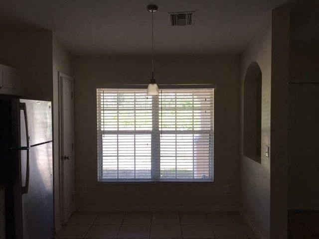 an empty room with a window and a refrigerator
