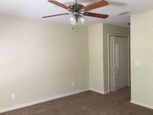 an empty living room with a ceiling fan and a door