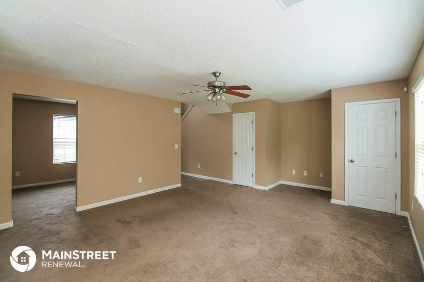 the living room of an empty house with a ceiling fan