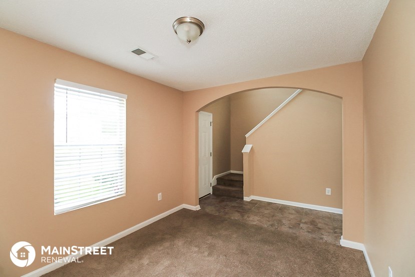 the living room of a home with a carpeted floor and a large window