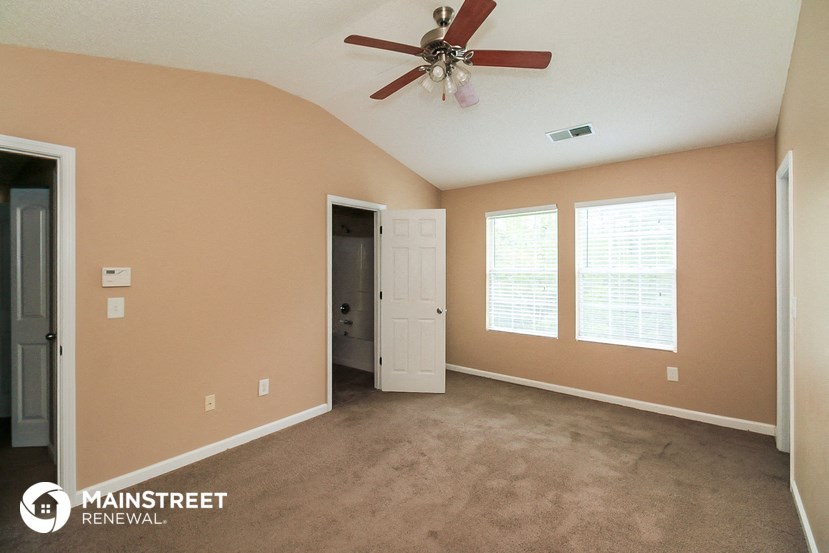 a carpeted room with a ceiling fan and a door to a closet