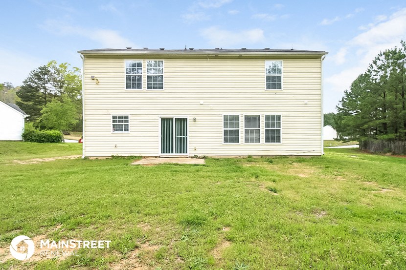 the back of a white house with a green door and grass