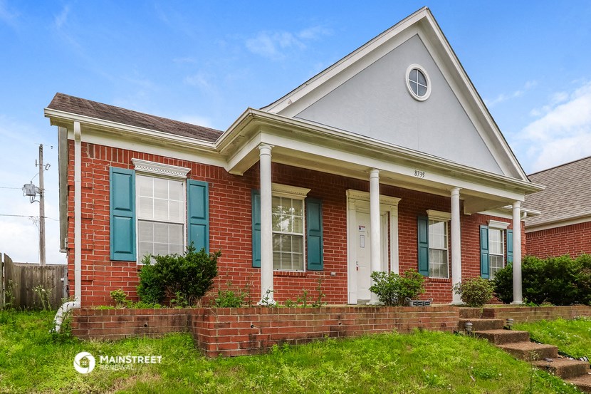 a brick house with blue shutters and a lawn