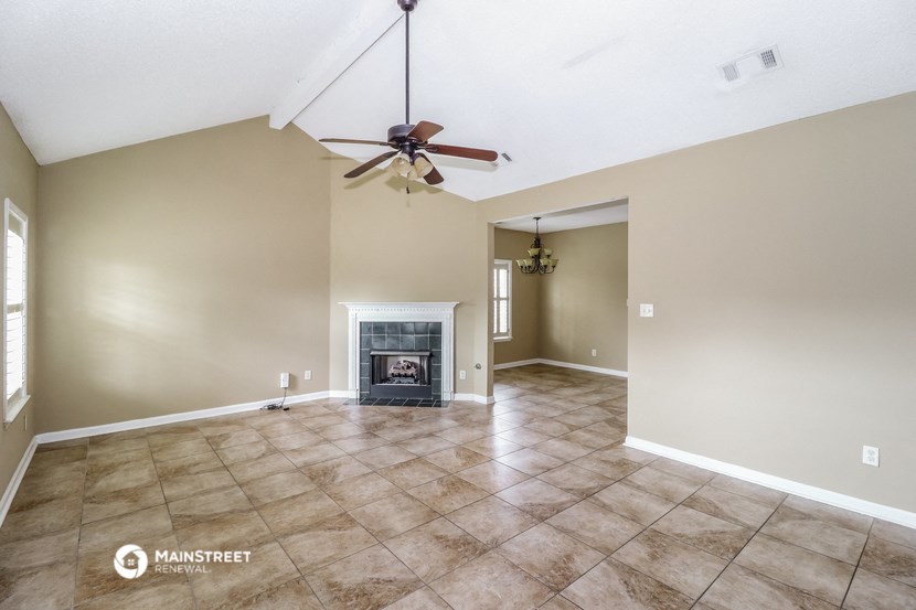 the living room with fireplace and tile flooring and a ceiling fan
