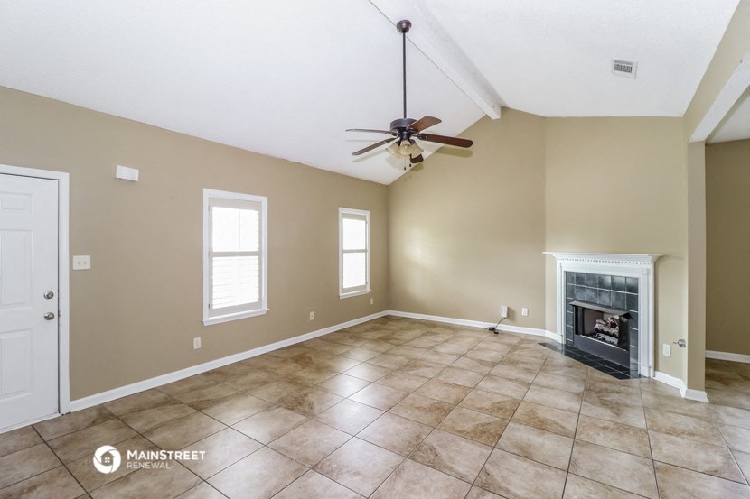 an empty living room with a fireplace and a ceiling fan